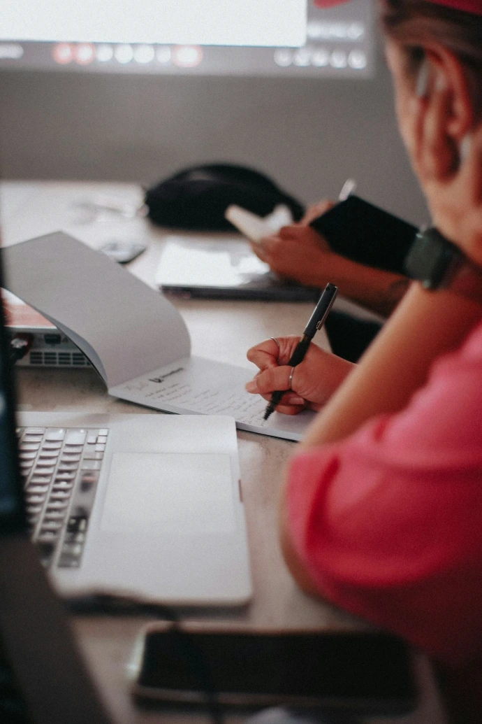 a woman sitting at a desk writing on a piece of paper